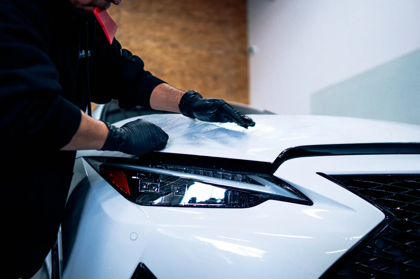 Installer fitting film to a hood during a paint protection film install